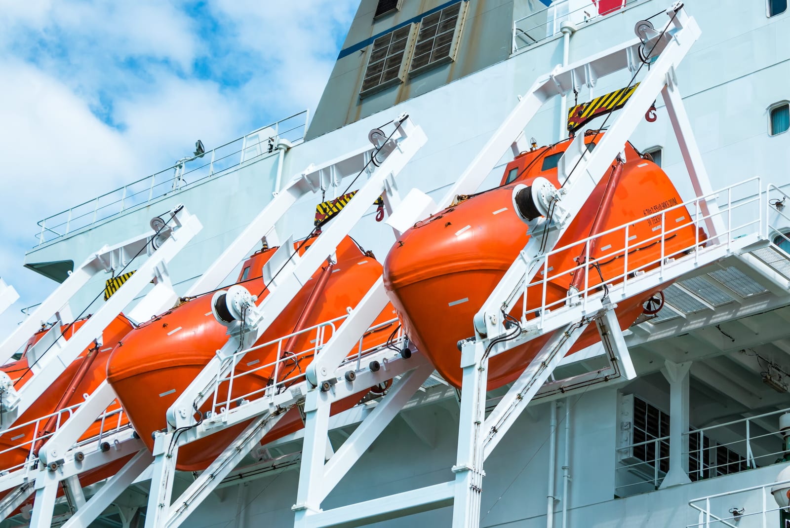 Orange davit launched totally enclosed lifeboats stowed on gravity davits along a ship's side