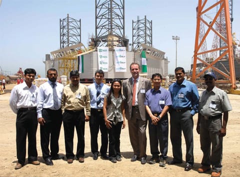 Client and contractor project team assembled at an offshore fabrication yard in front of a unit under construction
