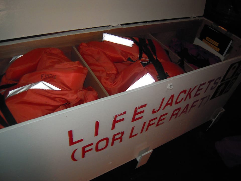 Deck locker stenciled life jackets for life raft holding orange lifejackets with reflective tape