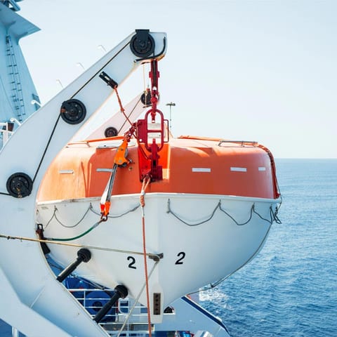 Orange enclosed lifeboat secured in its davit cradle