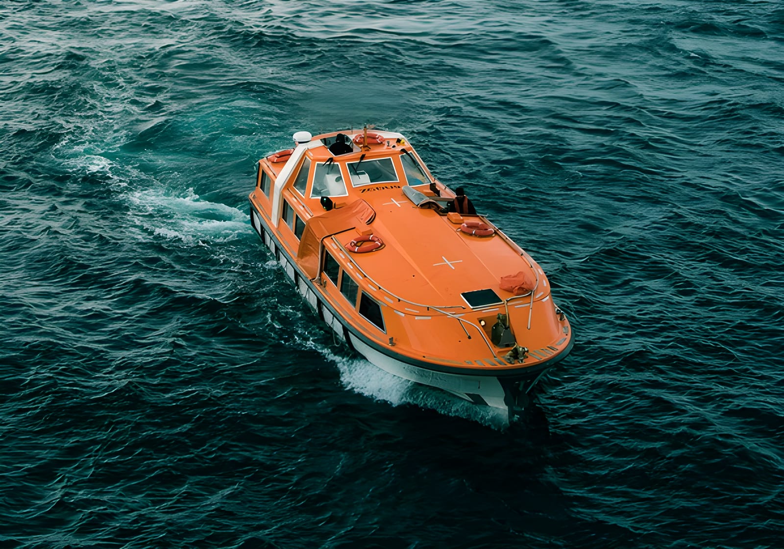 Enclosed orange lifeboat afloat at sea after launch