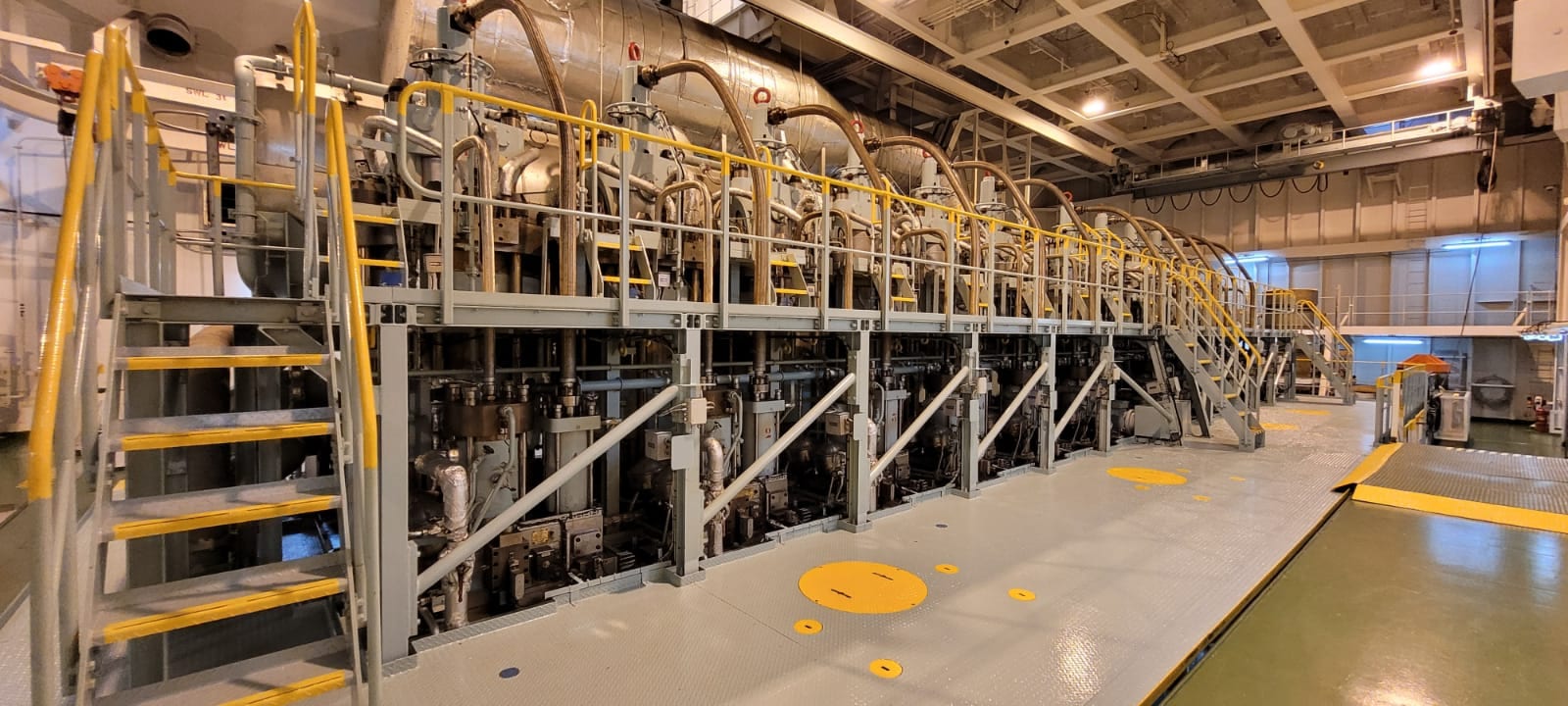 Main engine cylinder heads and railed walkways inside a ship's engine room