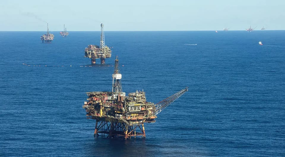 Fixed offshore production platforms spread across a calm sea toward the horizon