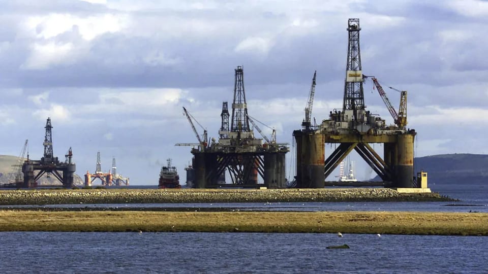 Semi submersible drilling rigs laid up in a coastal anchorage under a cloudy sky